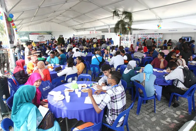 A large marquee full of attendees at round tables filling in forms, with the Career Day 2014 stage backdrop in the distance